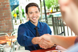 Young man shaking hands at table