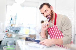 Bearded businessman in apron calculating